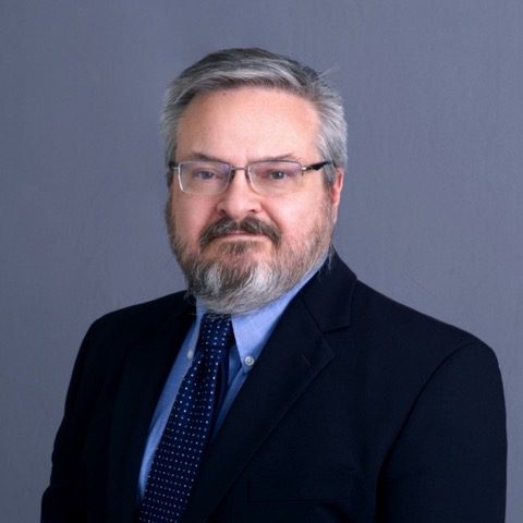 Professional portrait of a middle-aged man in a suit and tie.
